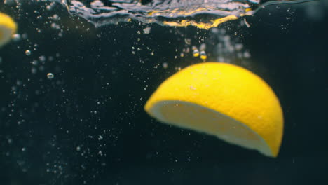 Zitrone-Spritzt-Ins-Wasser-Auf-Schwarzem-Hintergrund,-Nahaufnahme-In-Superzeitlupe